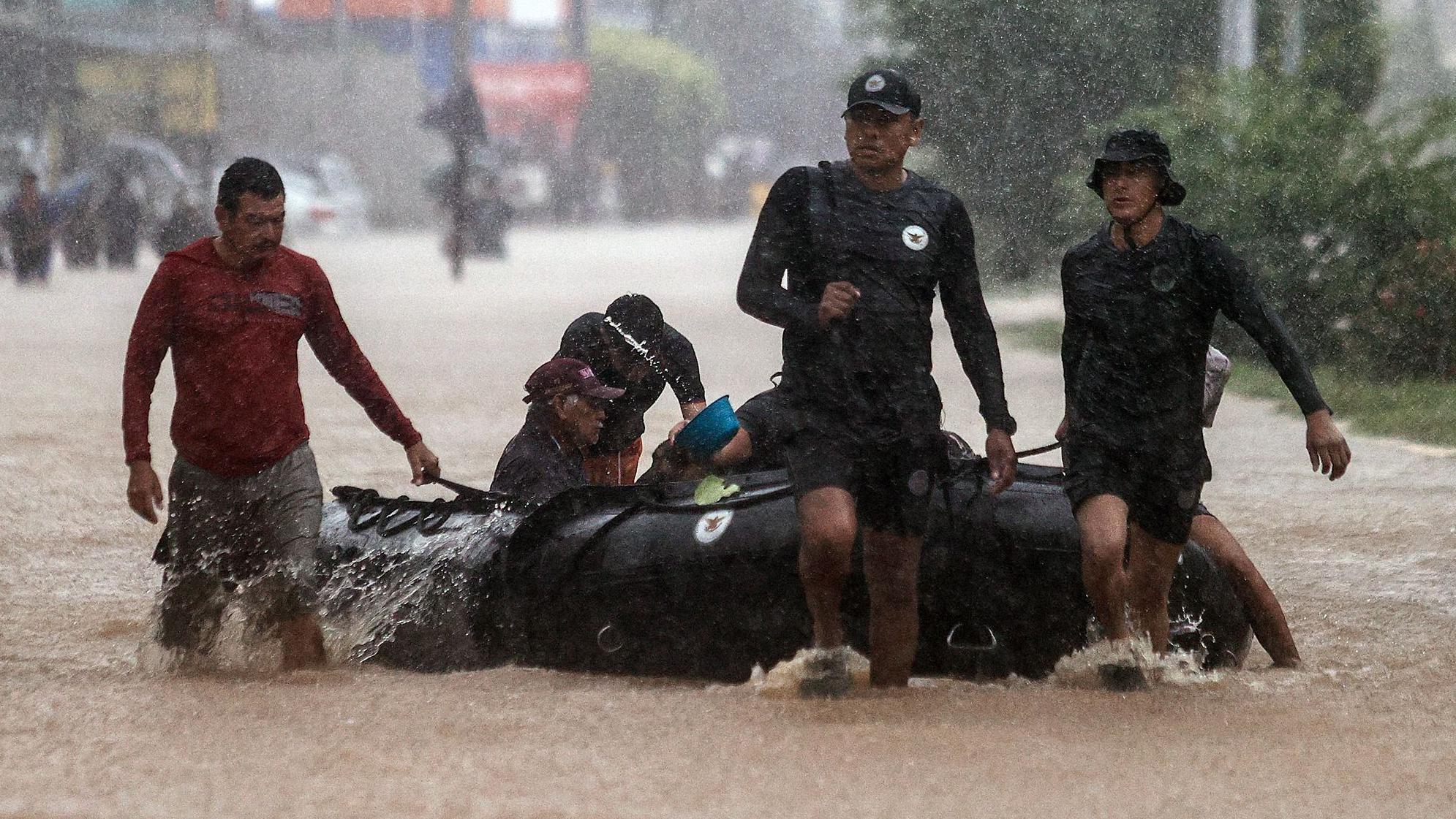 Unos hombres avanzan con una lancha en una calle inundada