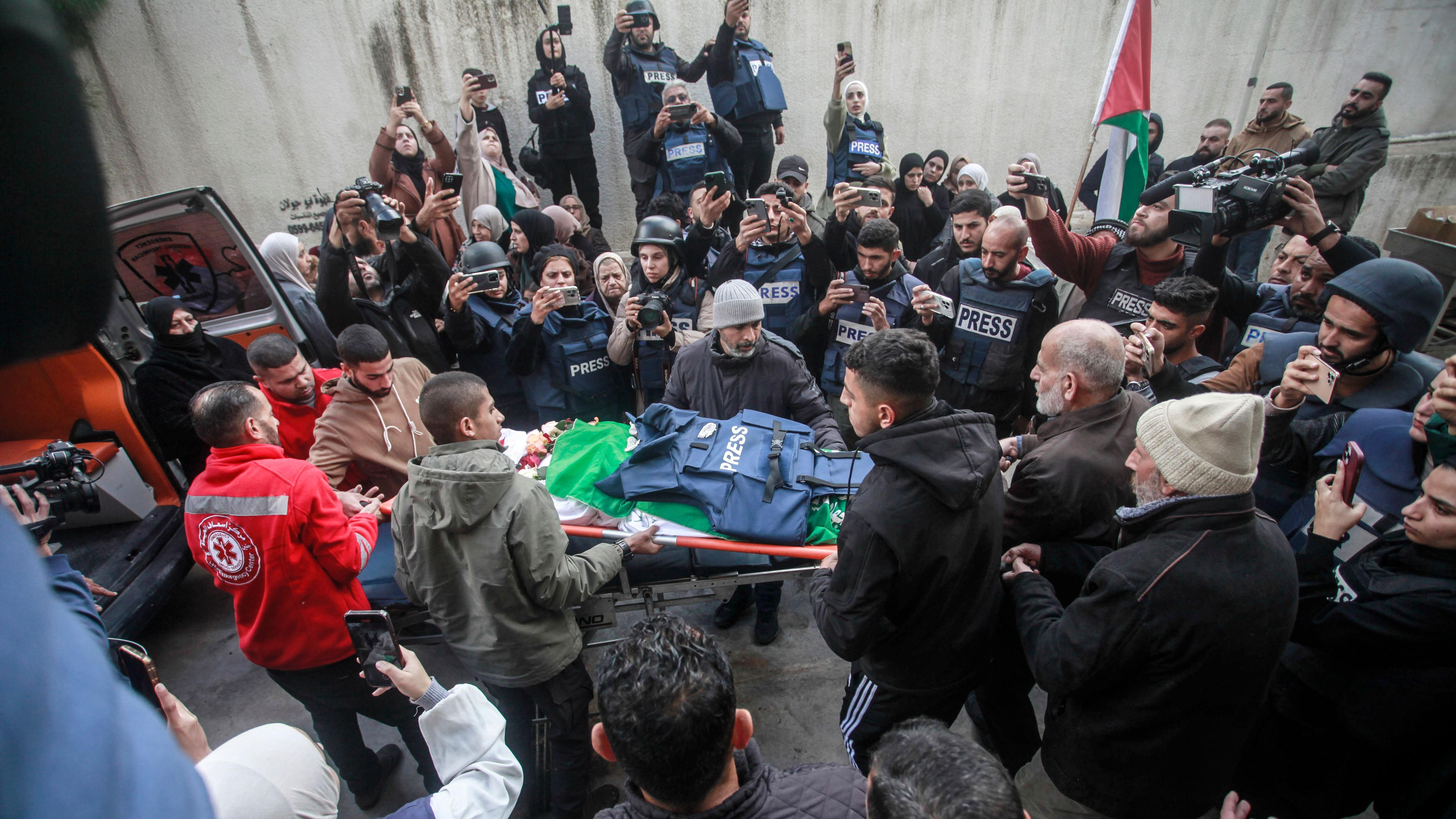 Palestinos enlutados e jornalistas carregam o corpo de Shatha al-Sabbagh, uma estudante de jornalismo, em frente ao Hospital Governamental de Jenin.