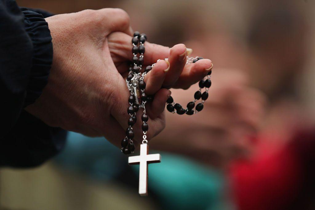 Una mujer sostiene un rosario mientras reza