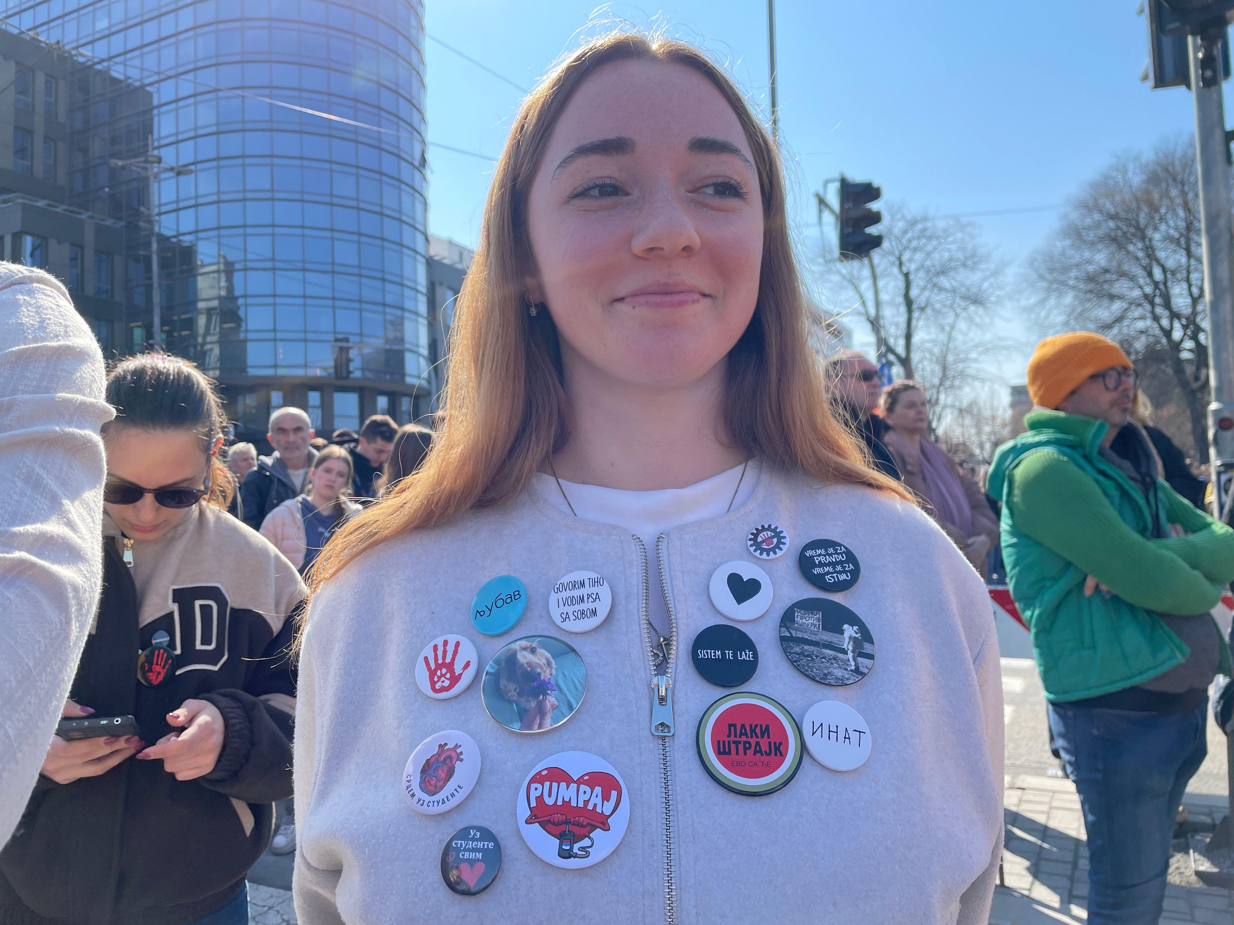 Jedna od studentkinja na protestu ispred Skupštine sa bedževima