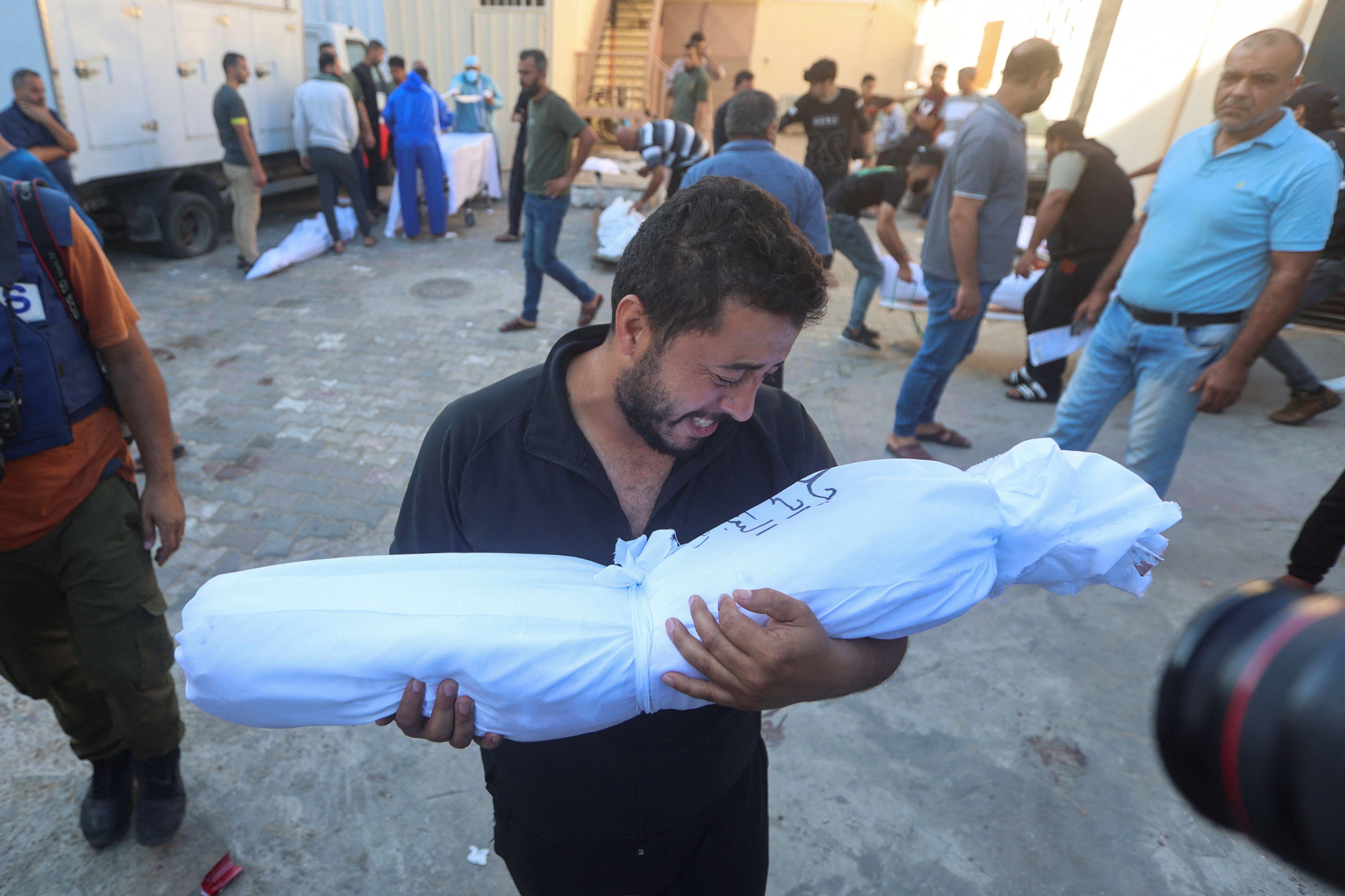 رجل فلسطيني يحمل جثة طفله من أمام مستشفى شهداء الأقصى بوسط قطاع غزة 
