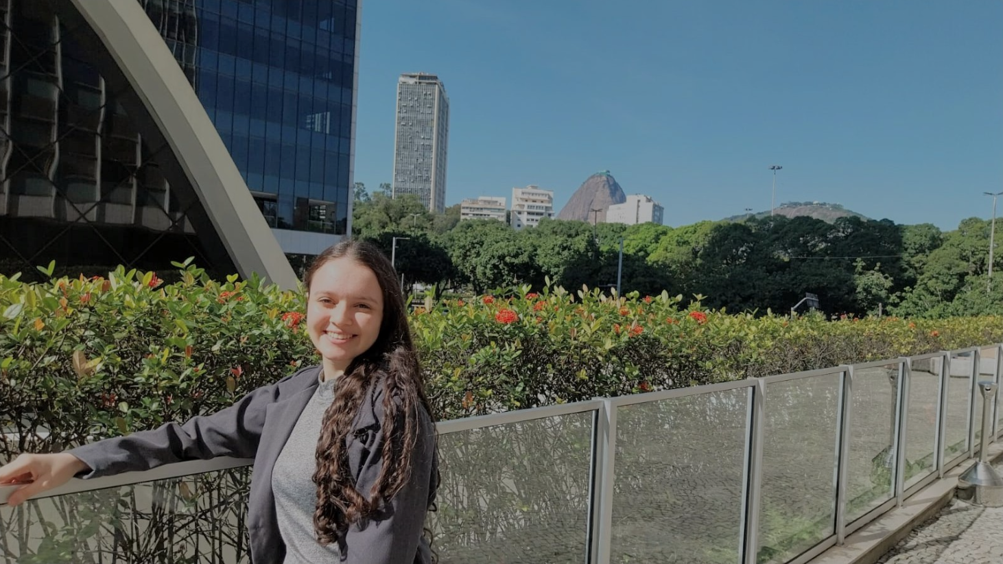 Paula sorrindo perto de jardim 