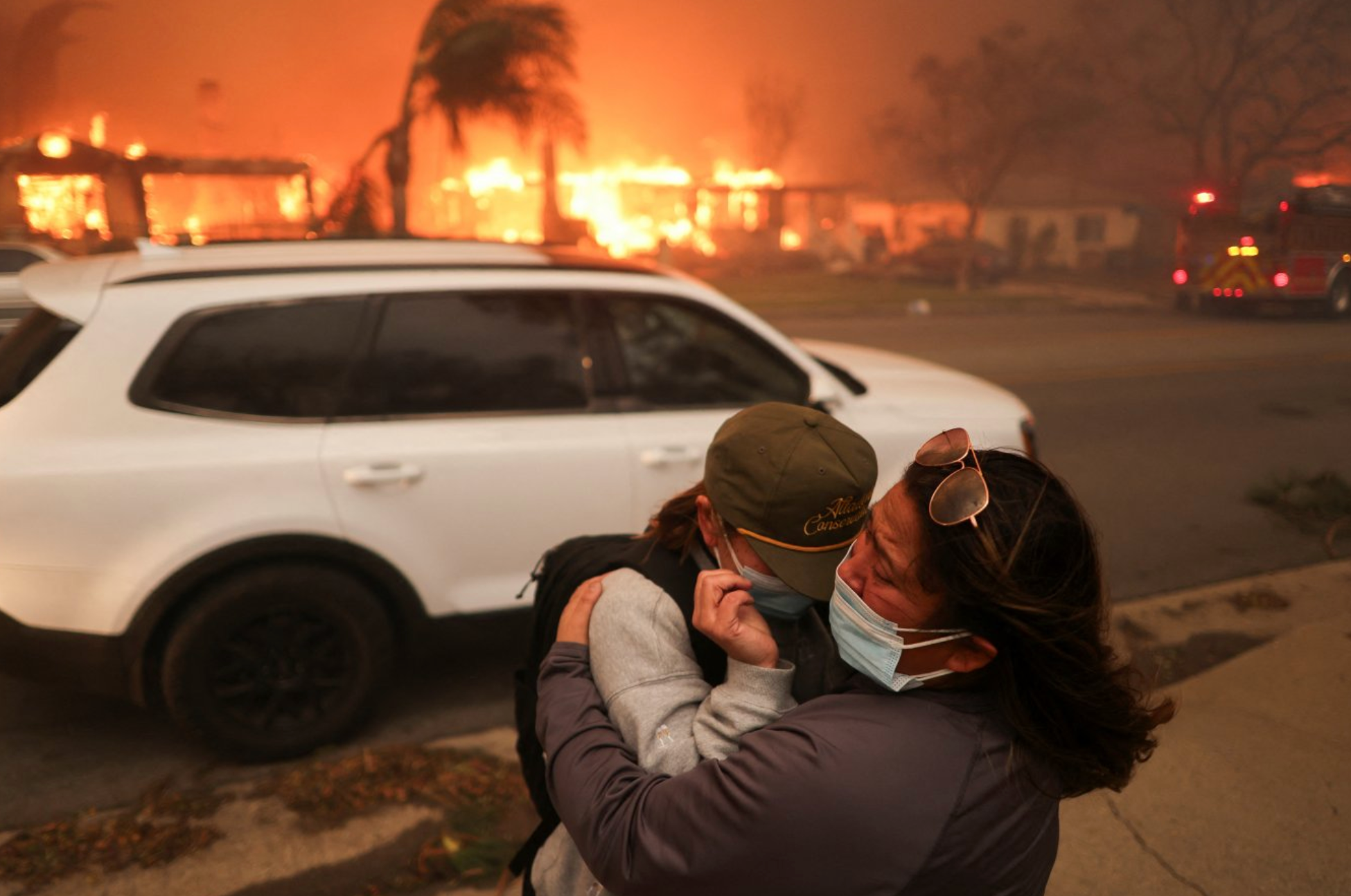 Duas pessoas se abraçam enquanto evacuam após fortes ventos que alimentam incêndios florestais devastadores na área de Los Angeles