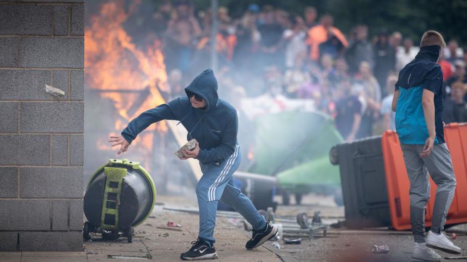 Un extremista arroja un ladrillo durante un disturbio en Reino Unido