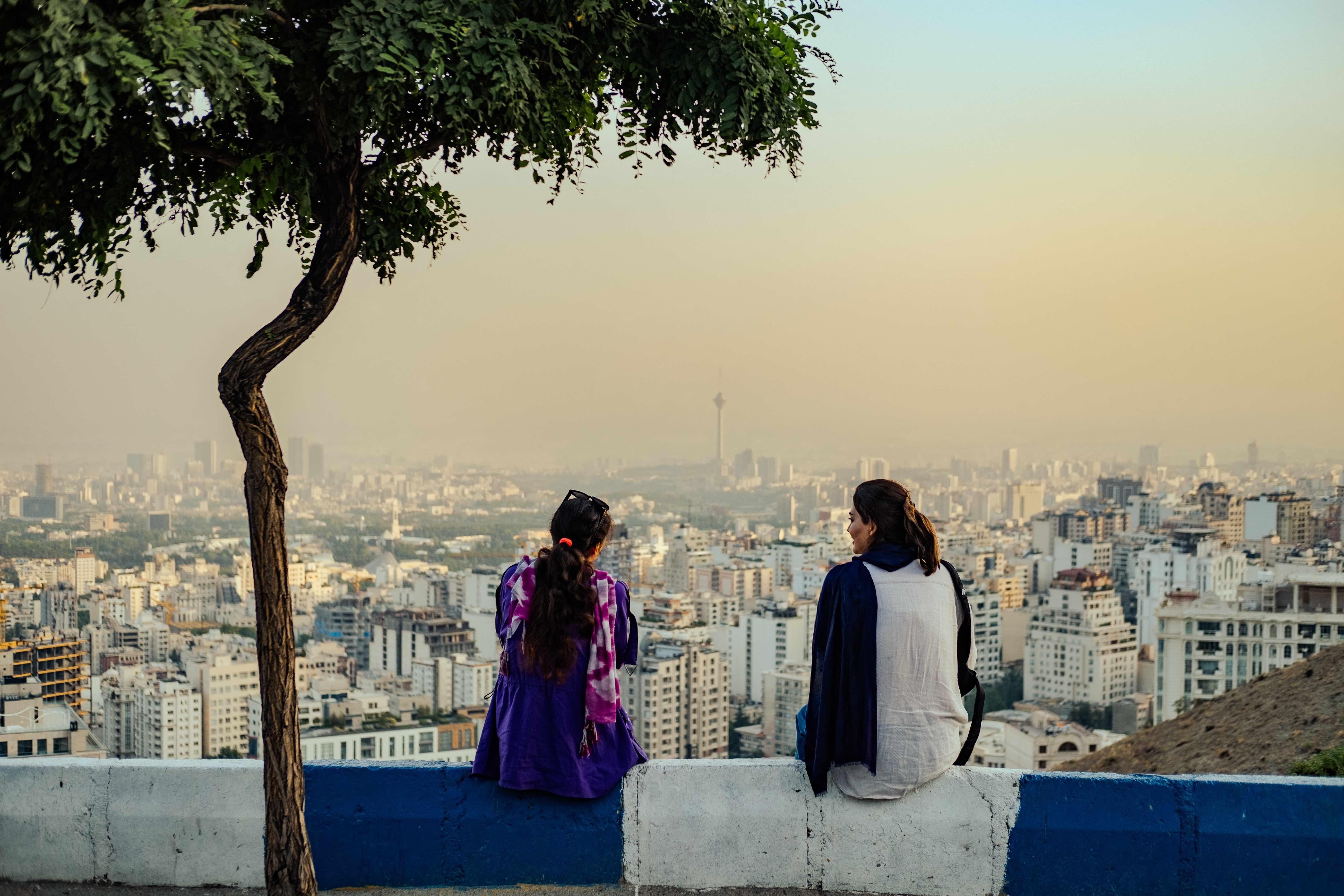 Mulheres iranianas sem o hijab obrigatório sentam-se em Bam-e Tehran (Telhado de Teerã) com vista para a cidade de Teerã, 2024