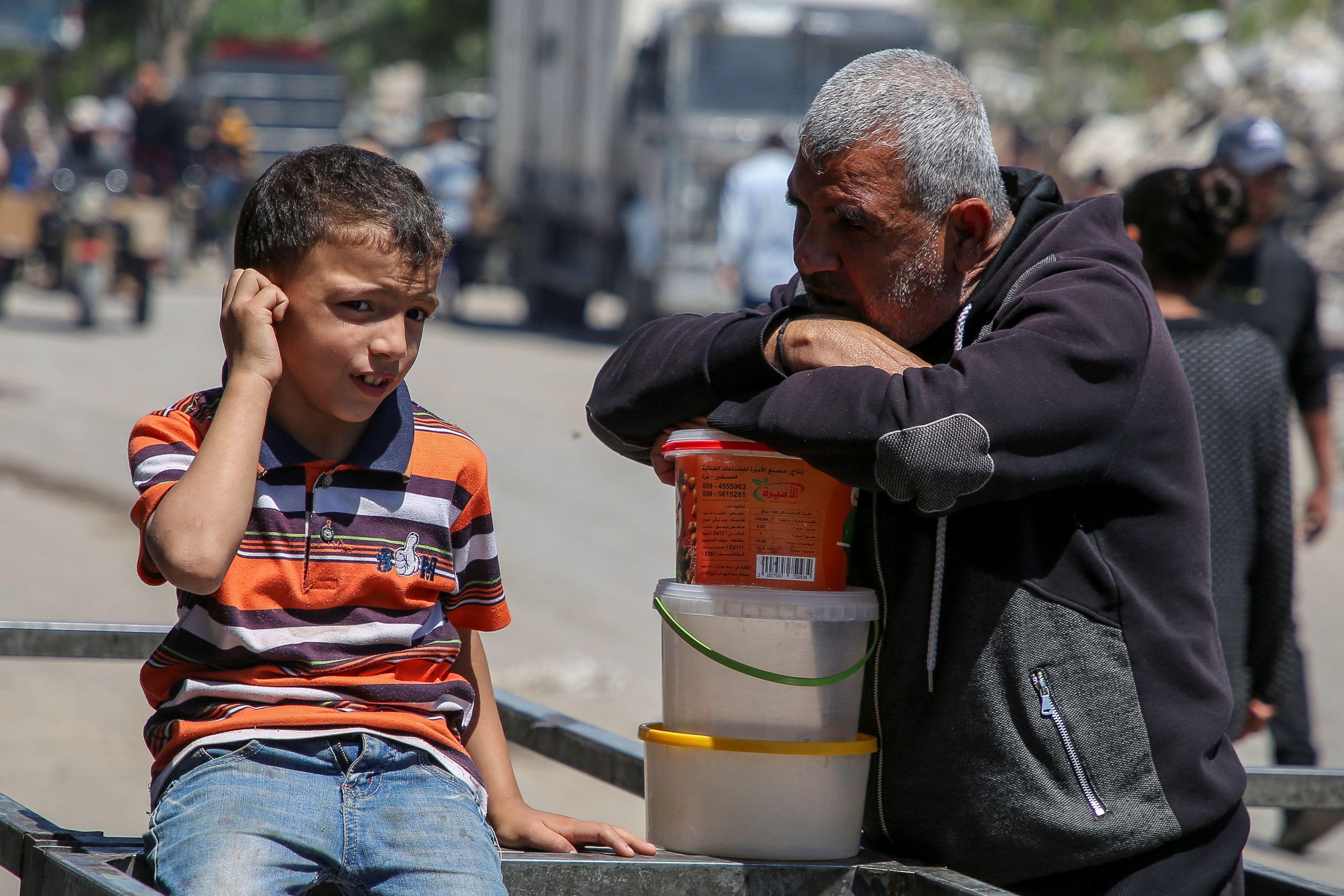 رجل وطفل فلسطينيان ينتظران الحصول على الطعام من مطبخ خيري، في ظل نقص إمدادات المساعدات، بعد أن شنت القوات الإسرائيلية عملية برية وجوية في الجزء الشرقي من رفح، 8 مايو/أيار 2024.