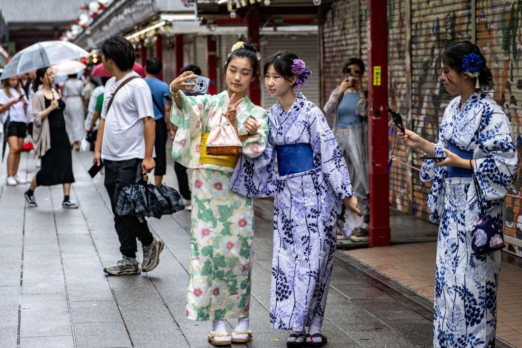 Três mulheres japonesas de quimono na rua.