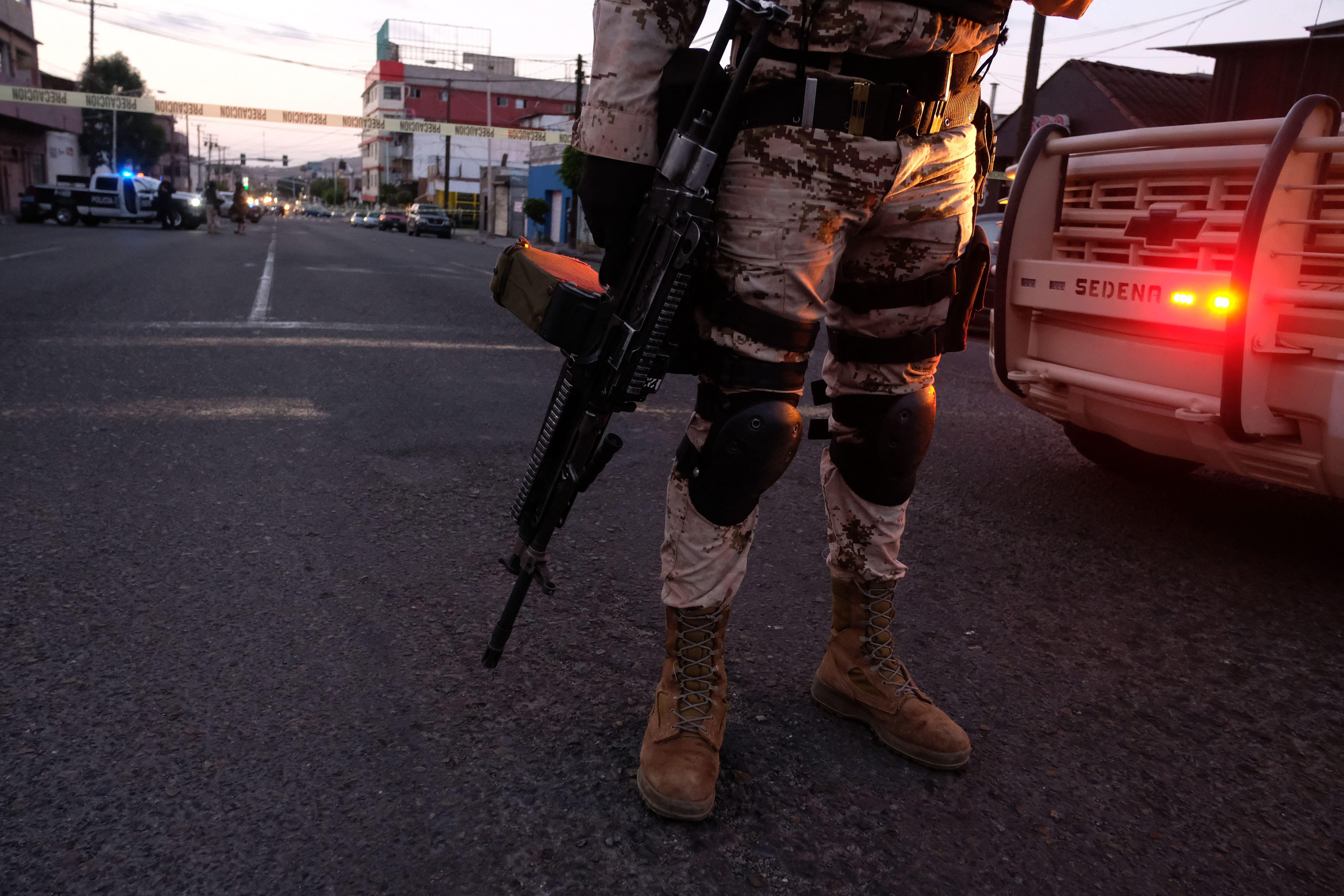 A Mexican soldier carries his long gun at a crime scene