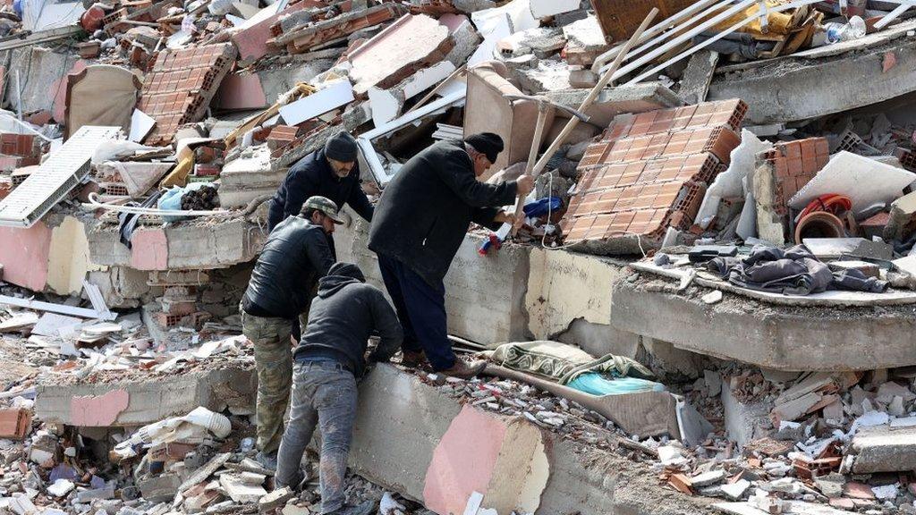 Pessoas trabalham para remover os destroços de um prédio que desabou em Kahramanmaras, perto do epicentro do terremoto