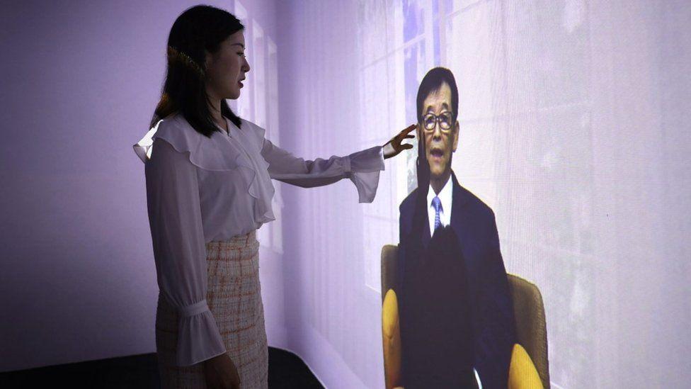 Una mujer tocando el avatar de un familiar realizado por la firma coreana Deepbrain AI.