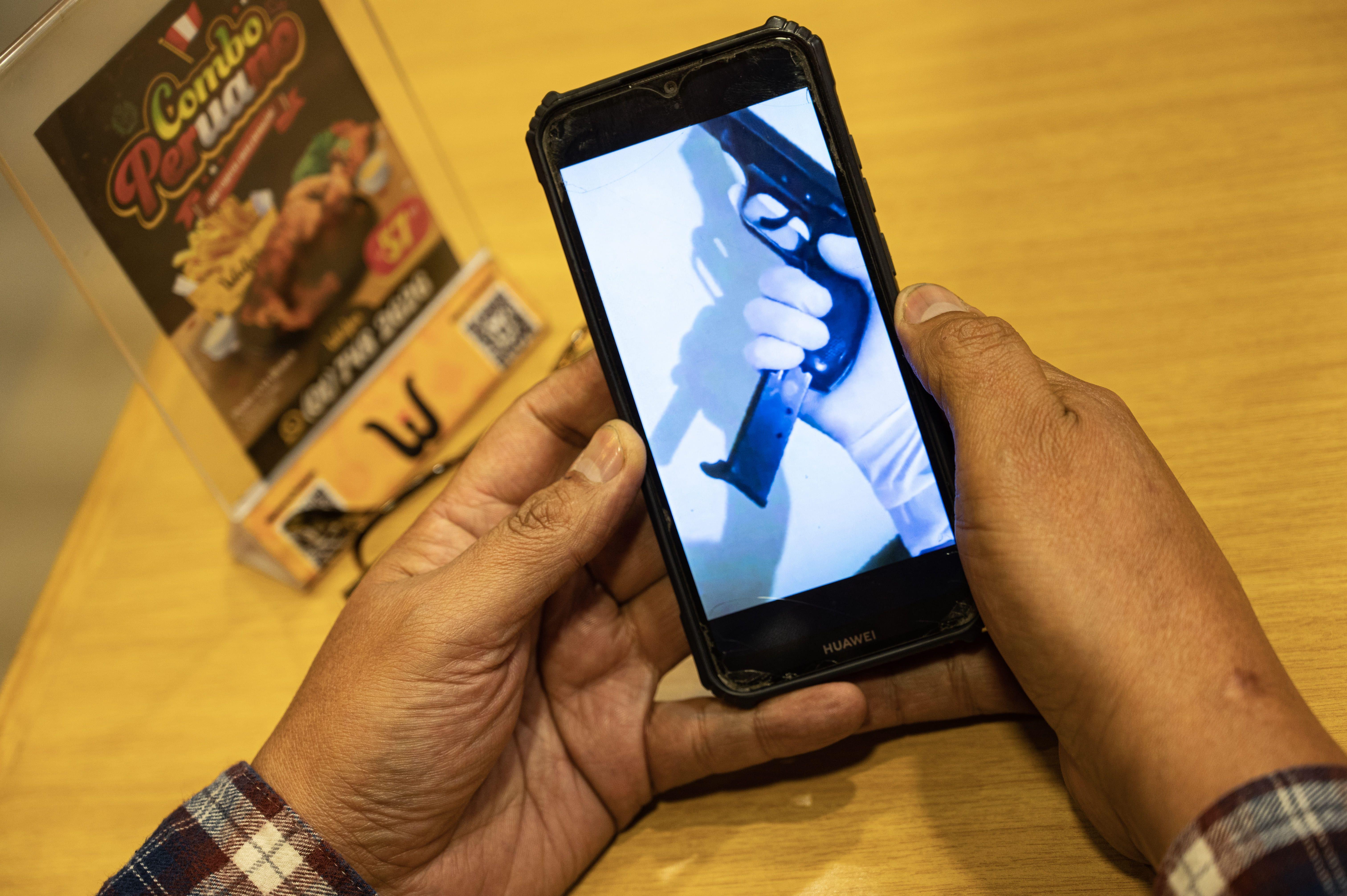 Un hombre muestra en su teléfono el video en el que lo amenazan.