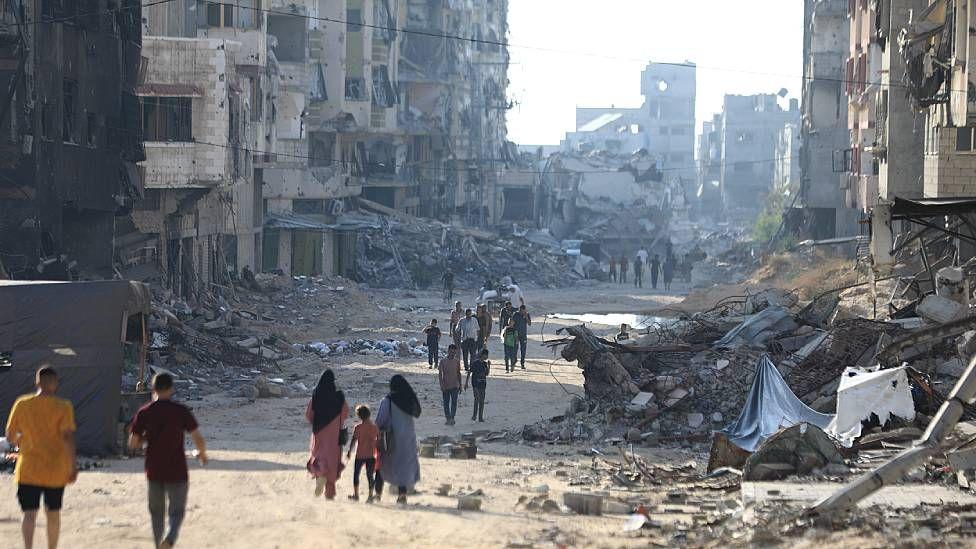Personas caminando entre edificios en ruinas en la Ciudad de Gaza 