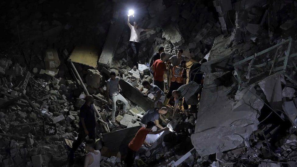 Rescuers comb the rubble of St Porphyrius Church illuminated by a portable light