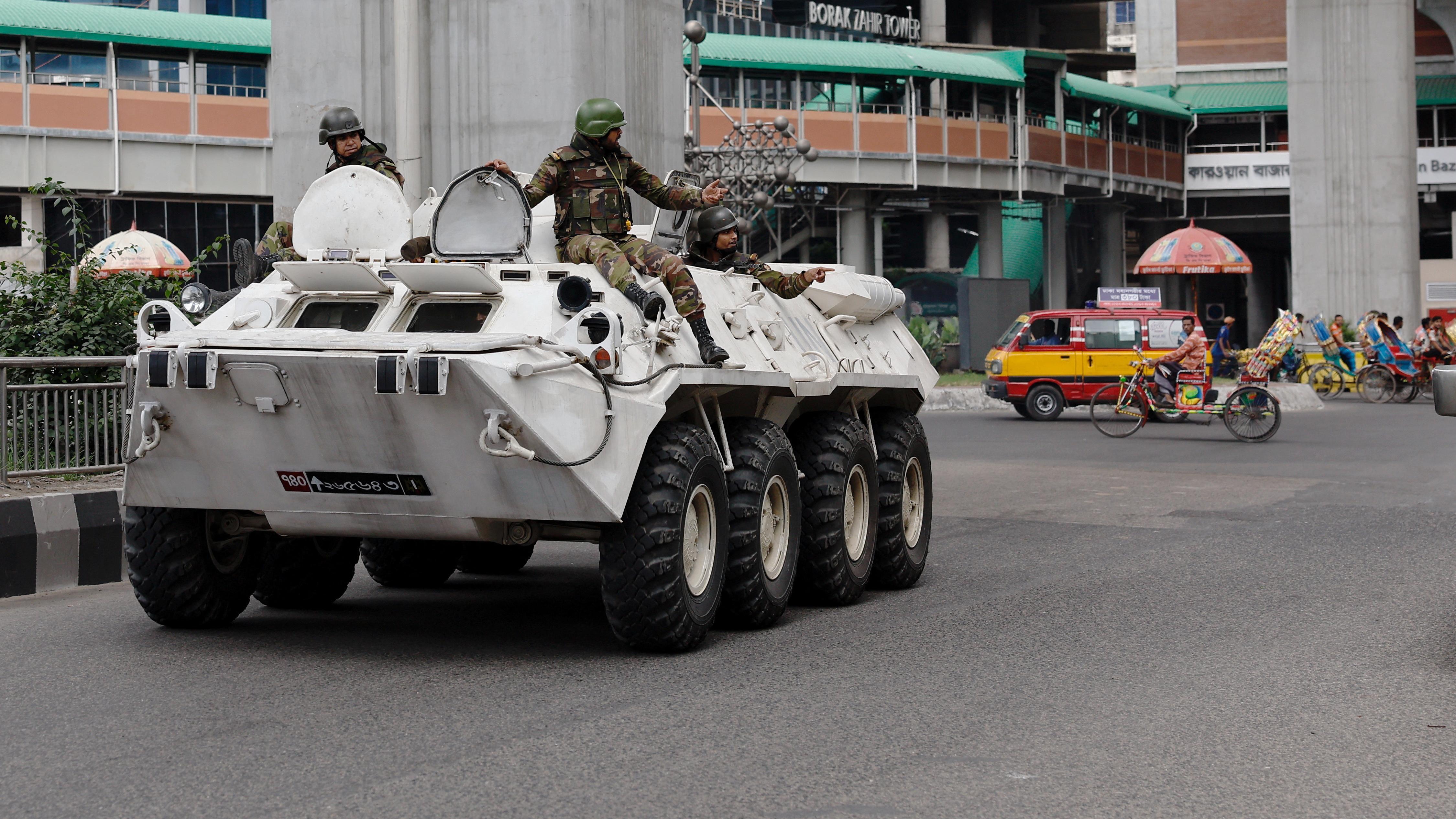 Three soldiers in a white tank wave their arms to direct people and traffic on a near empty street