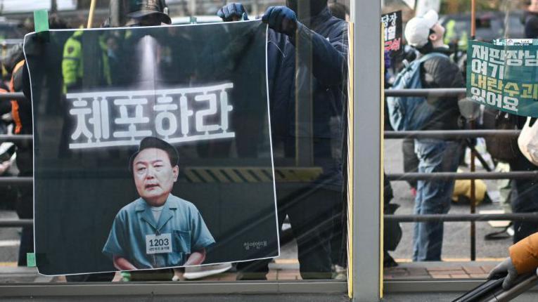 윤석열 대통령을 체포하라는 현수막을 한 집회 참가자가 들고 있다