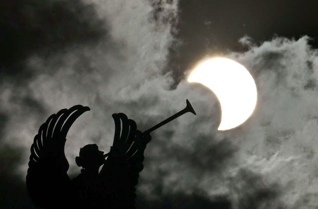 Vista parcial del eclipse anular solar junto al monumento de los ángeles en el Congreso Nacional en Buenos Aires.