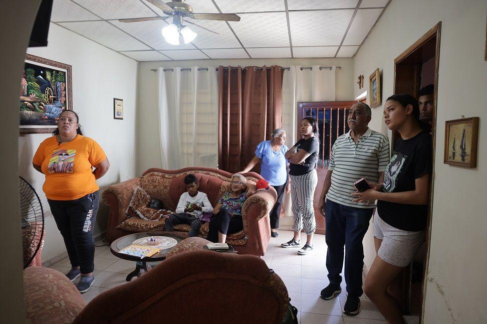 Myrelis Casique López viendo el televisor con otros familiares en la sala de una casa