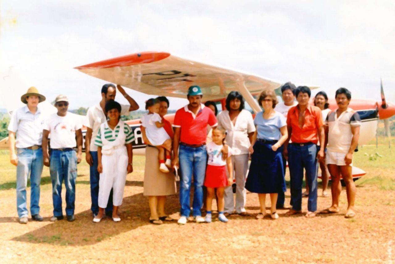 Fotografía de personas blancas y personas indígenas juntas en un espacio abierto.