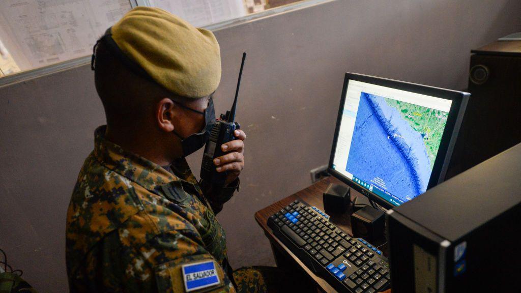 Un militar habla por radio mientras mira un mapa en su computadora