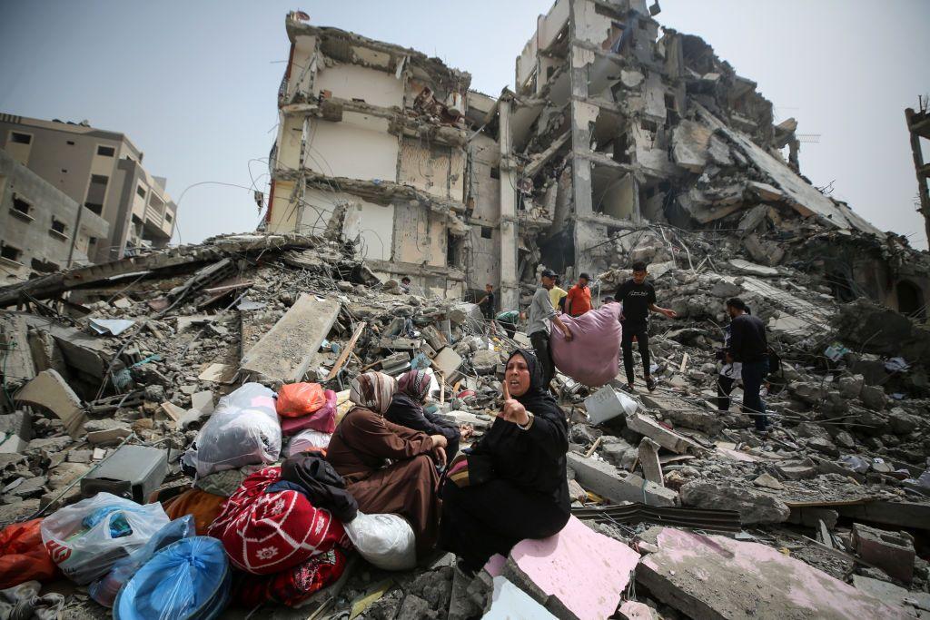 Mujeres palestinas reaccionan sentadas sobre los escombros de un edificio residencial que albergaba sus apartamentos en Gaza.
