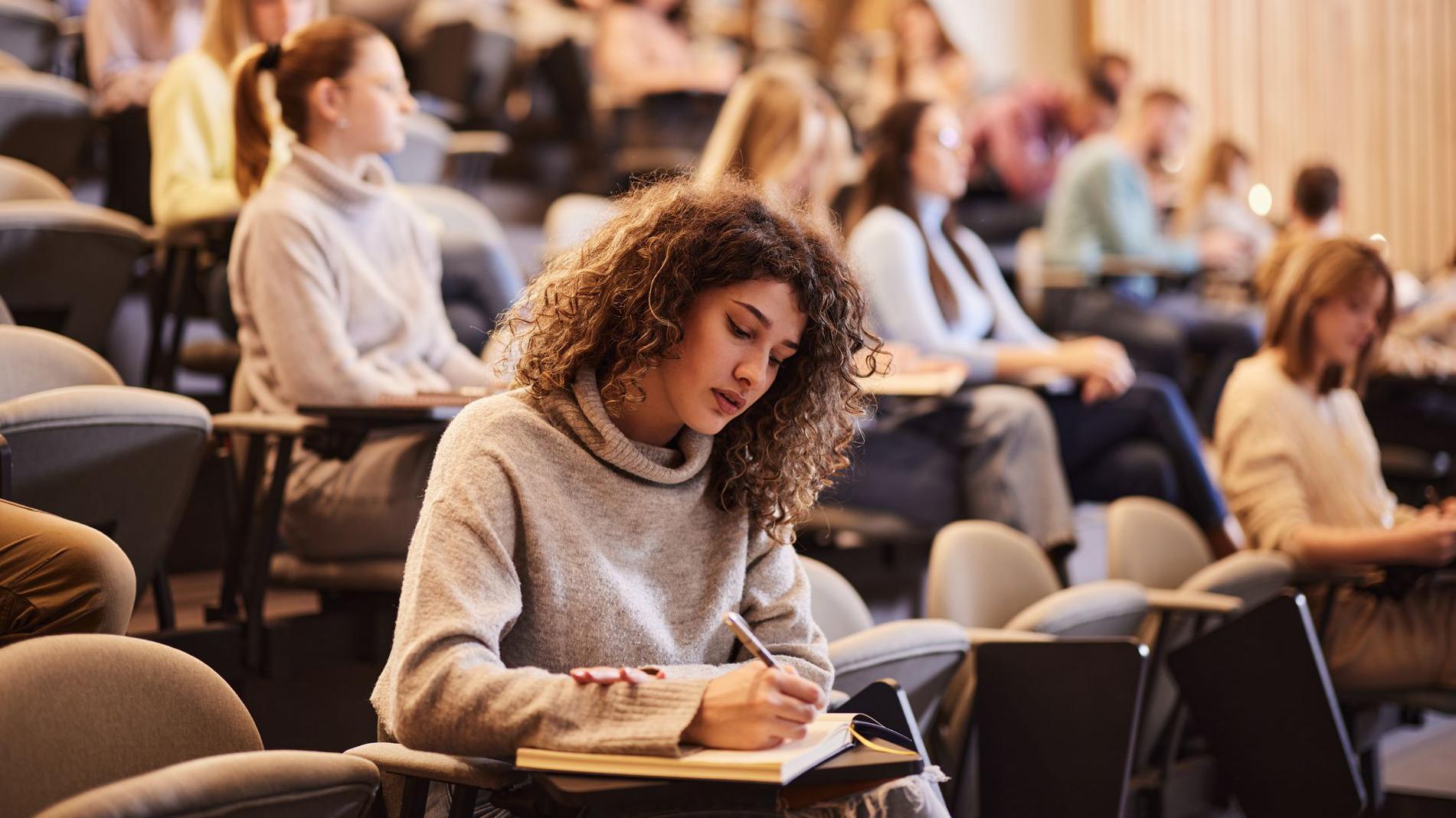 Joven tomando notas en un clase 