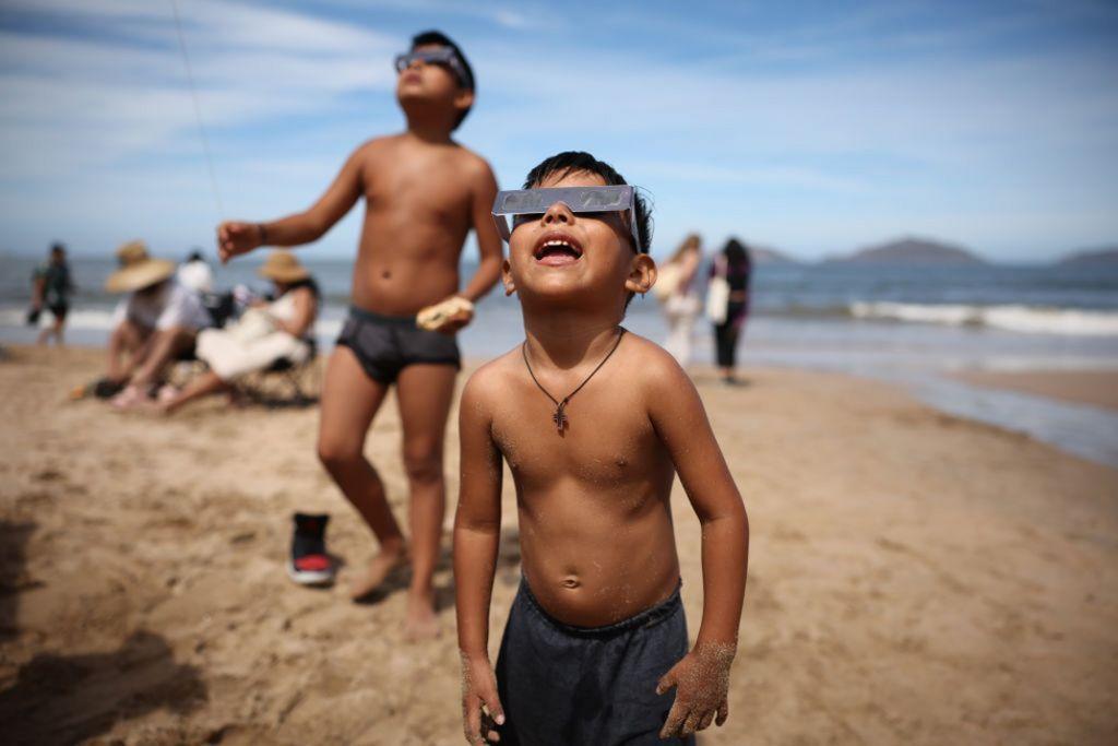 توقف الأطفال عن لعبهم على الشاطئ مؤقتاً لمشاهدة الكسوف في المكسيك