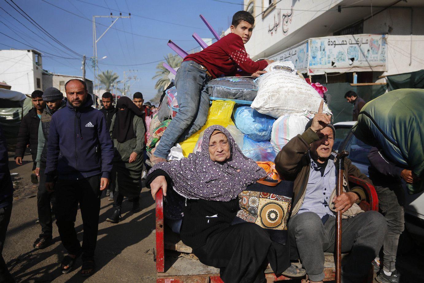 Palestinian citizens carrying their belongings leave their homes in Al-Maghazi refugee camp to seek safer places in the city as Israeli attacks continue in Deir al-Balah, Gaza on 4 January 2024.