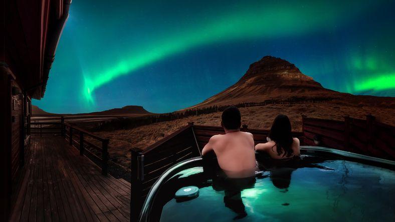 Casal observando a aurora boreal em piscina aquecida na Islândia