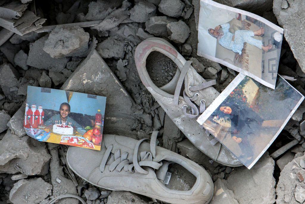 Cetakan foto pribadi dan sepatu kets berserakan di antara puing-puing bangunan yang hancur setelah serangan udara Israel di desa Qana, Lebanon selatan, 16 Oktober 2024. 