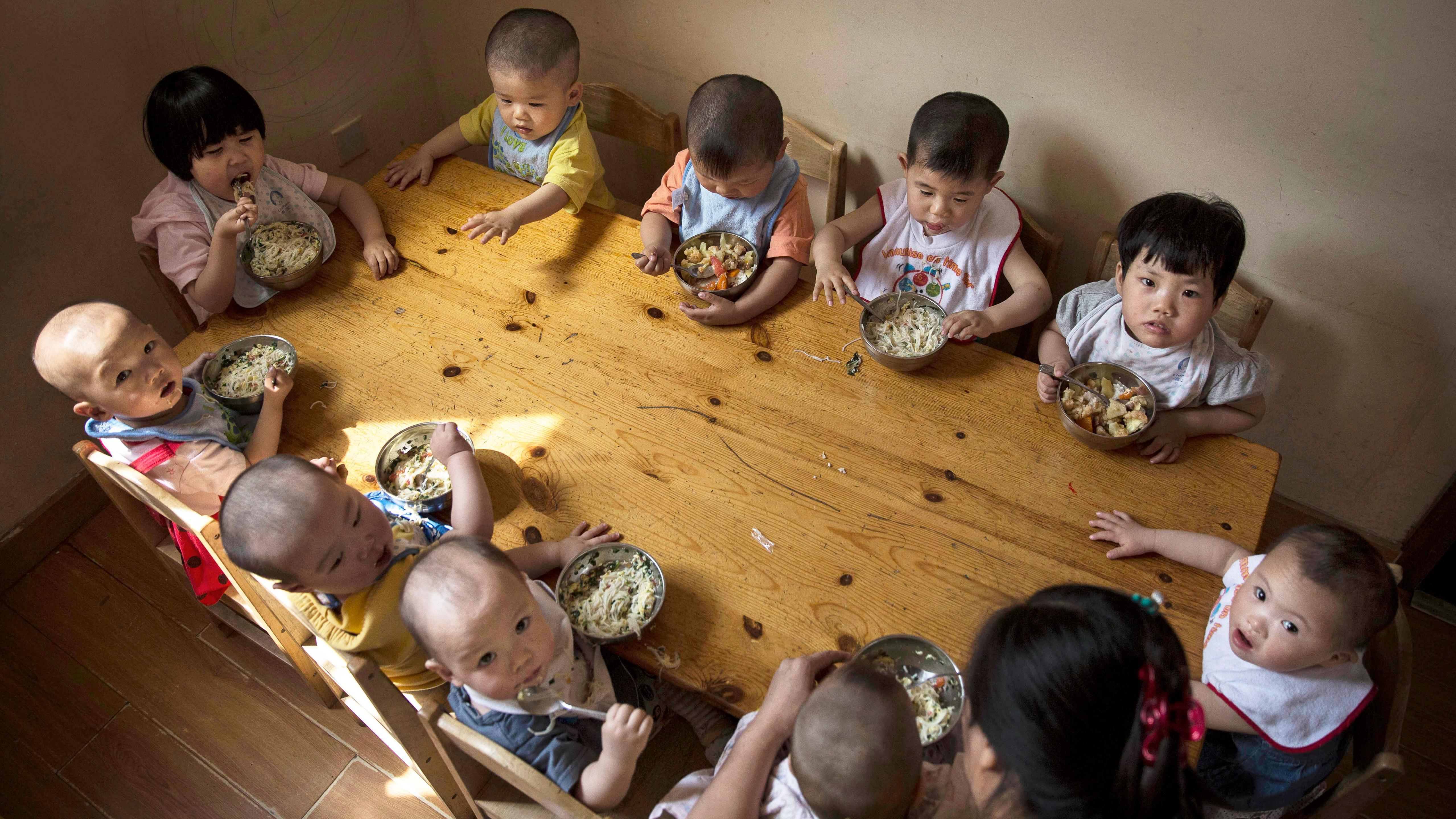 Young orphaned Chinese children eat a meal during feeding at a foster care center on April 2, 2014 in Beijing