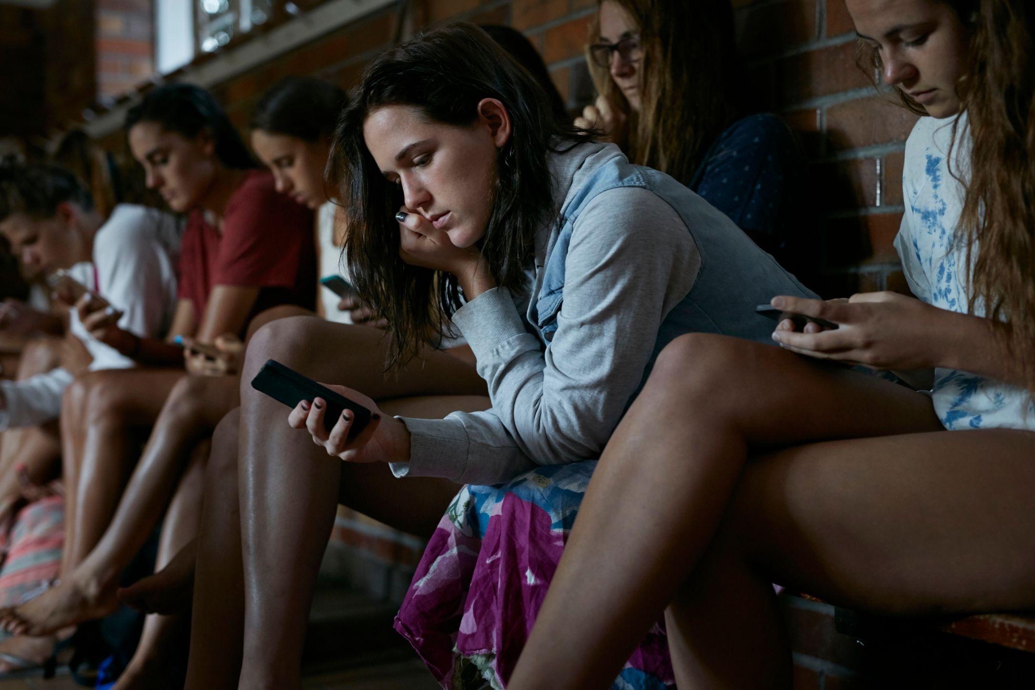 Estudiantes adolescentes mirando sus teléfonos inteligentes