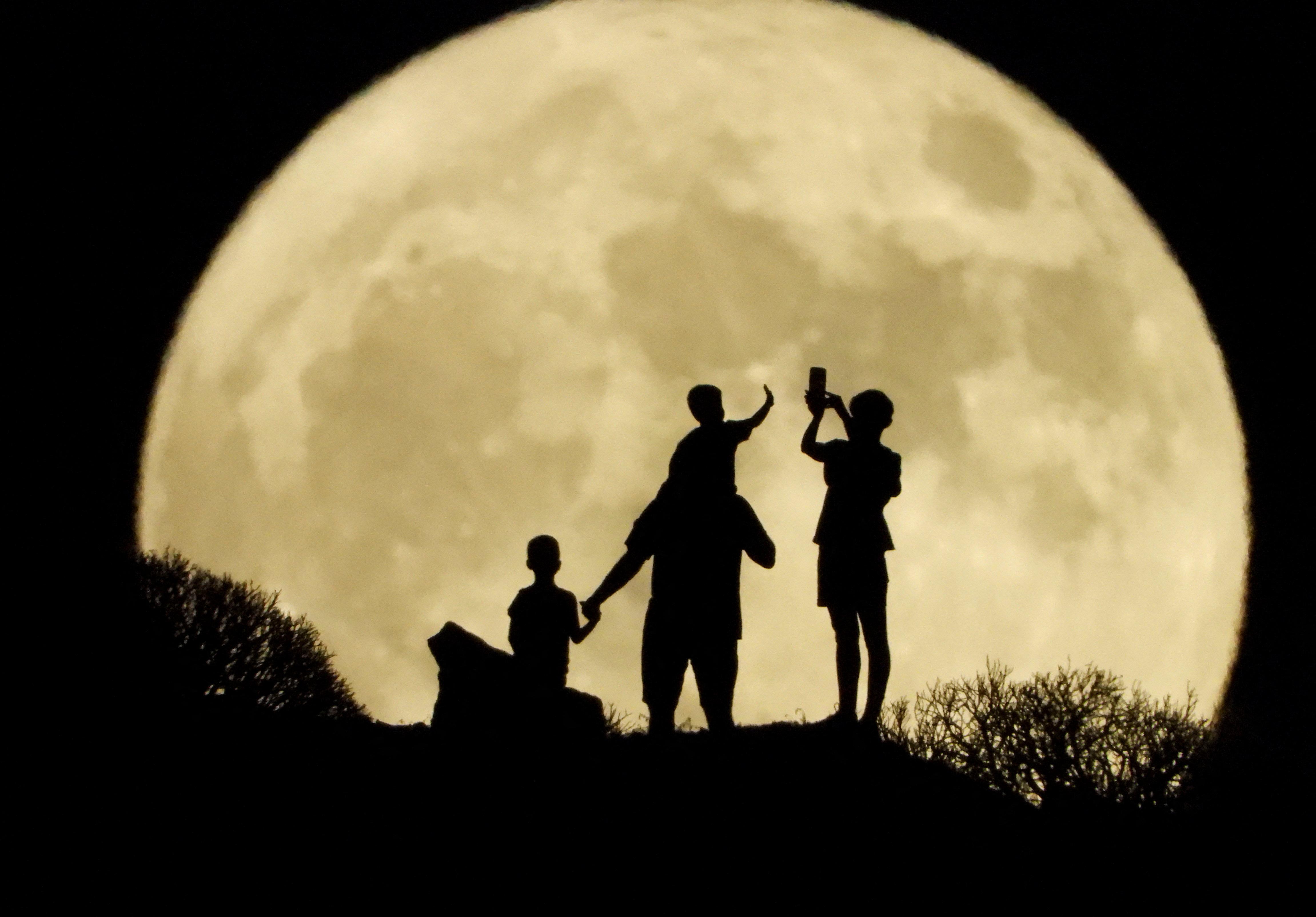La silueta de una familia frete a la Luna en Arguineguín, Gran Canaria, España.