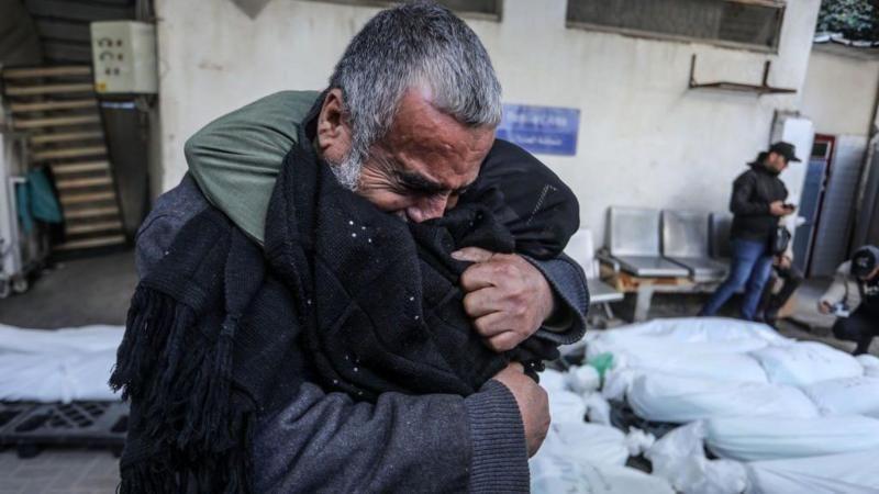 Homem abraça criança em meio a ataques na Faixa de Gaza