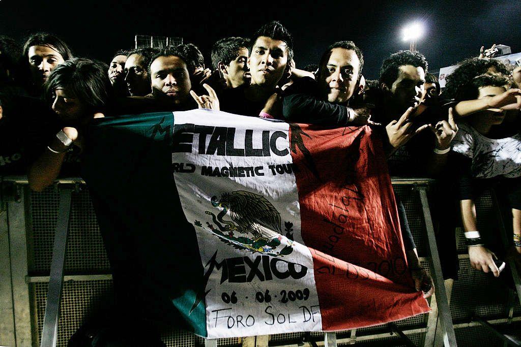 Unos aficionados del metal en México sostienen una bandera mexicana durante un concierto de Metallica