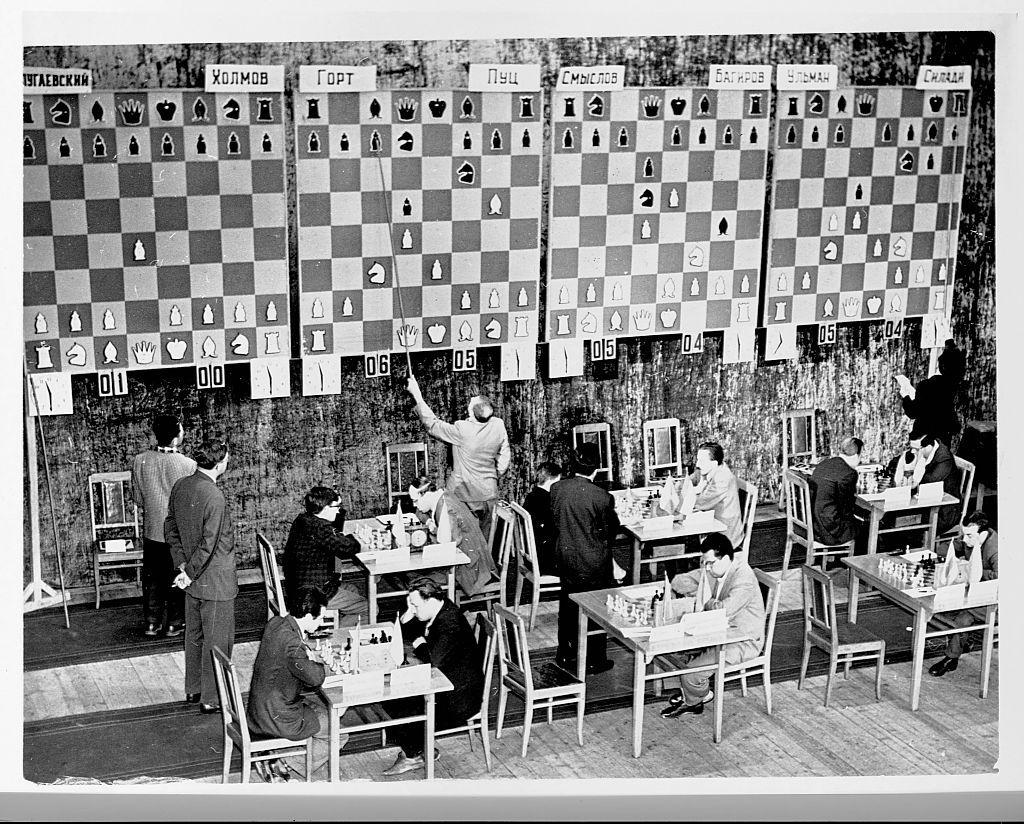 Jugadores de ajedrez y paneles con las partidas en un torneo de ajedrez de 1960.