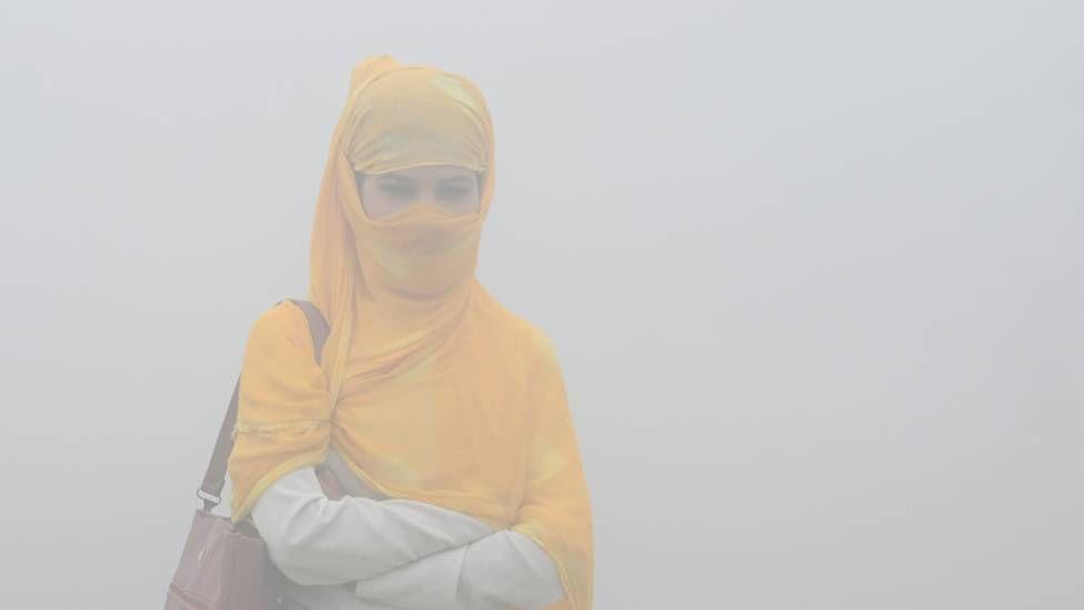 Una mujer caminando en medio de una neblina gris