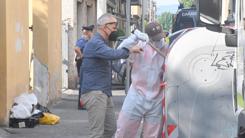 Policemen inspecting a garbage container