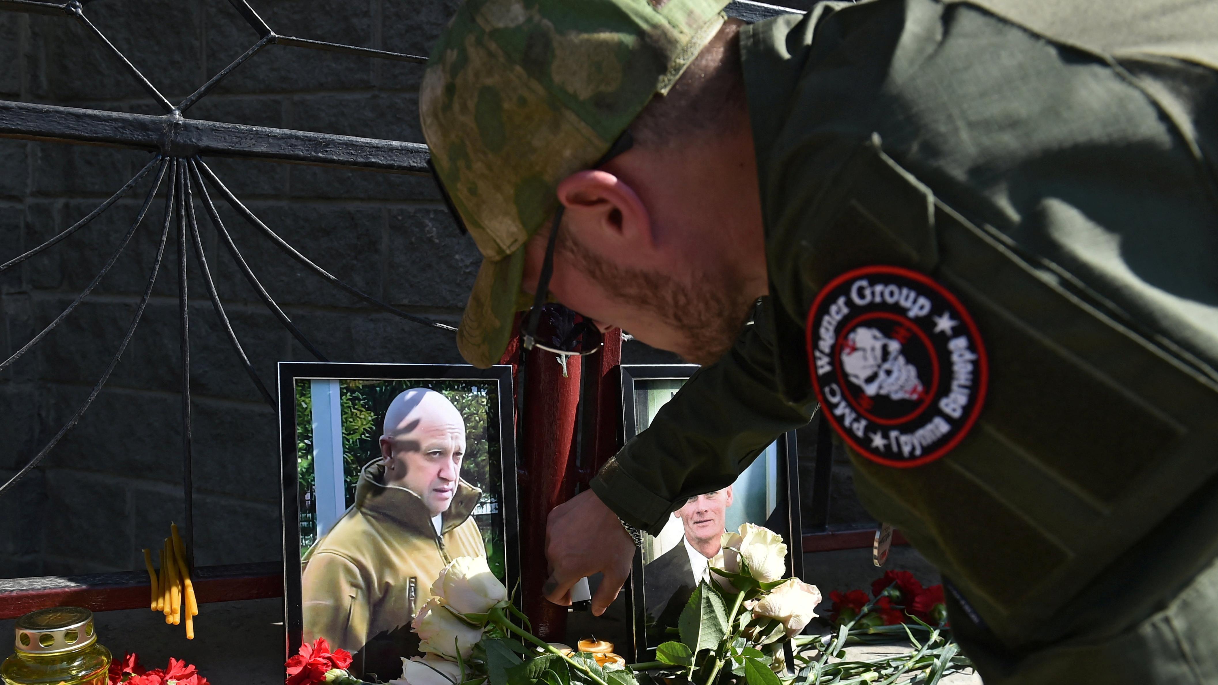 مقاتل من مجموعة فاغنر يضيء شمعة في نصب تذكاري مؤقت به صور لرئيس المرتزقة الروسي يفغيني بريغوجين