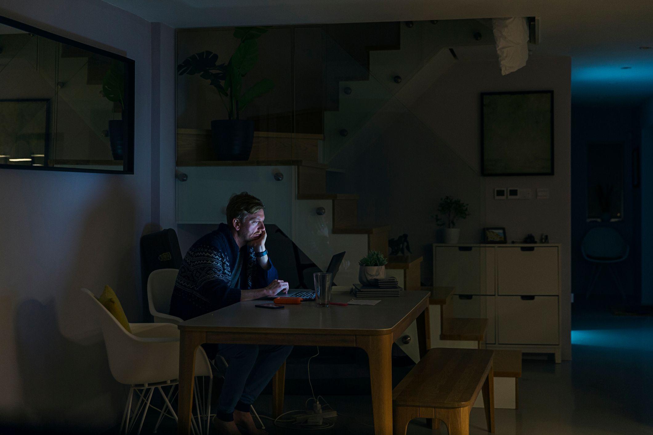 Homem trabalhando no laptop em ambiente escuro
