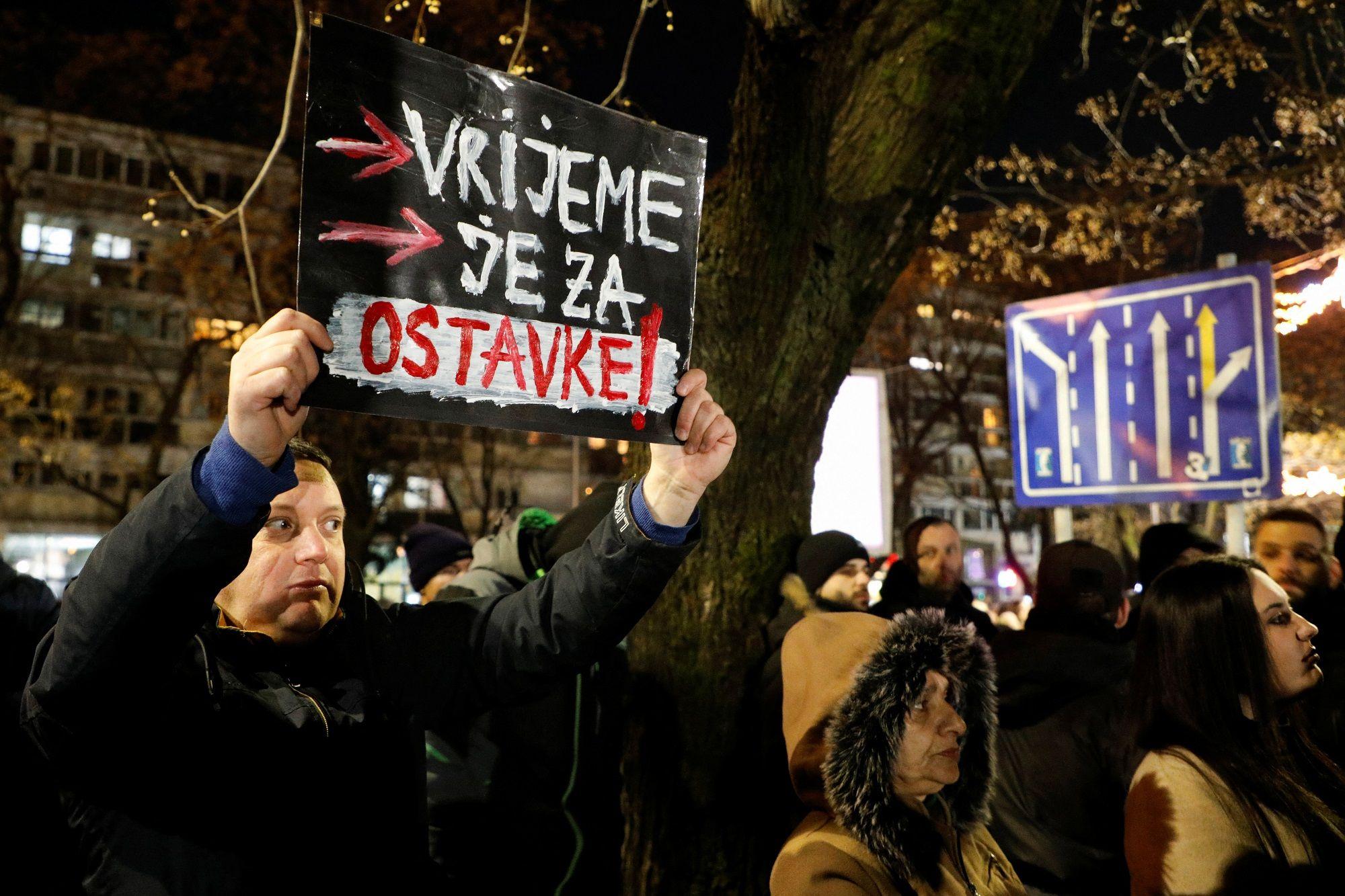 Muškarac drži transparent Vrijeme je za ostavke 