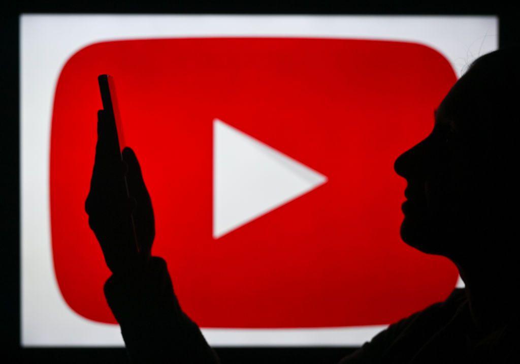 Ilustração da silhueta de uma pessoa fazendo selfie com celular com o ícone do Youtube ao fundo