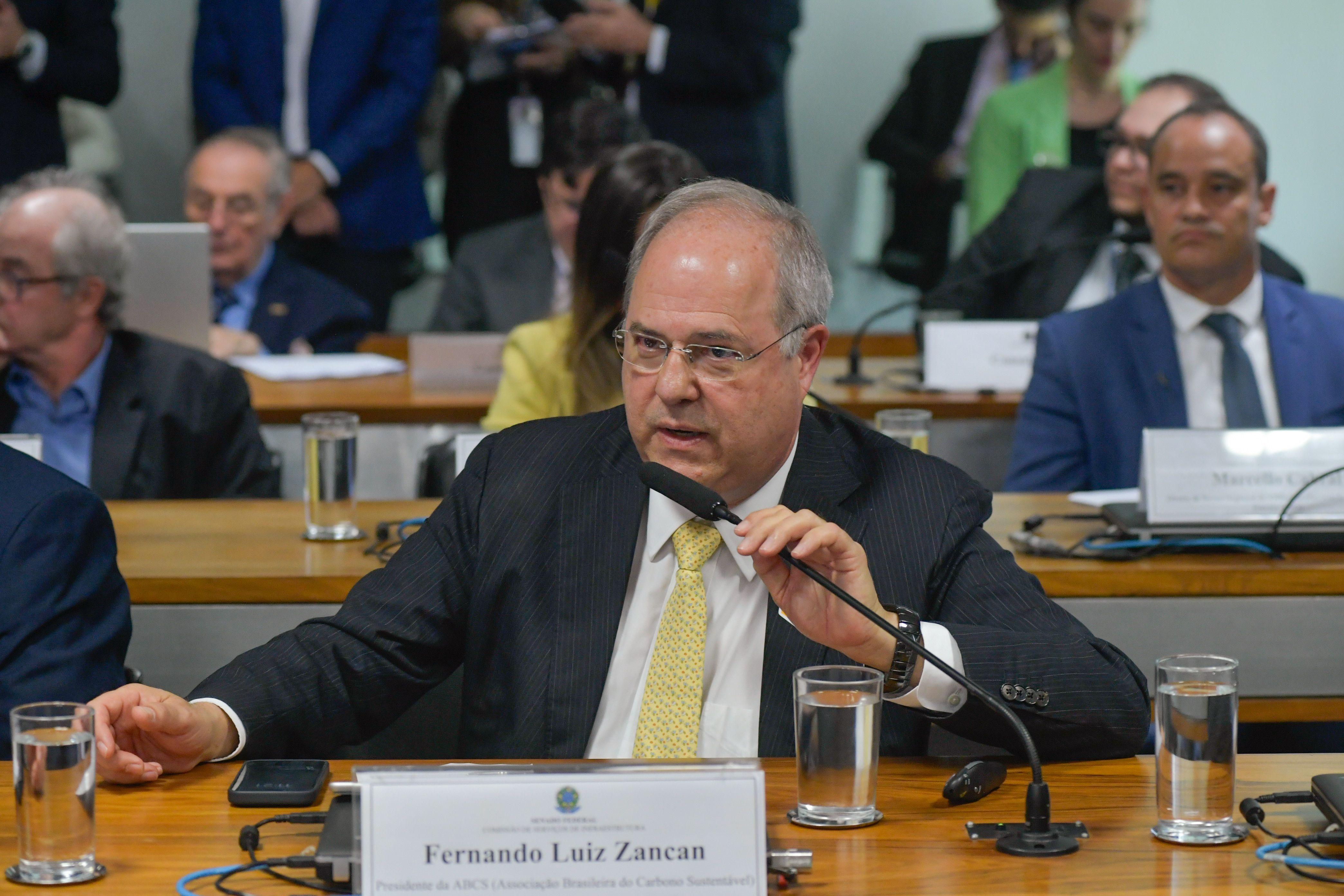 Fernando Luiz Zancan usando terno cinza e gravata amarela falando ao microfone do Senado