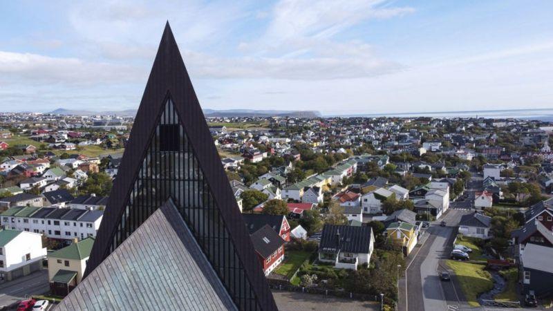 Imagem aérea mostra prédio triangular em meio a casas