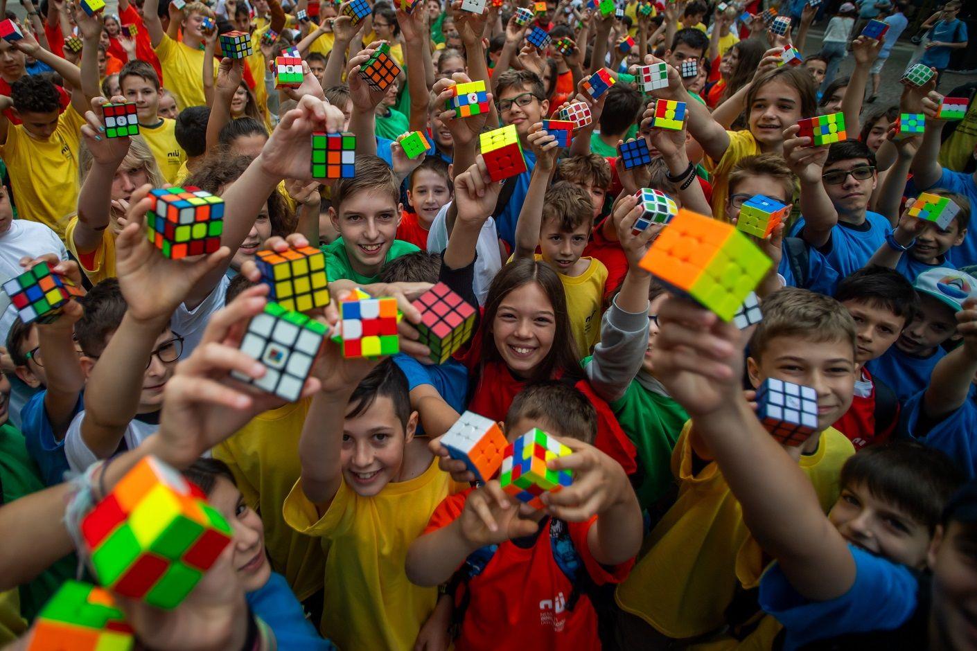 Dezenas de crianças sorrindo e levantando cubos 