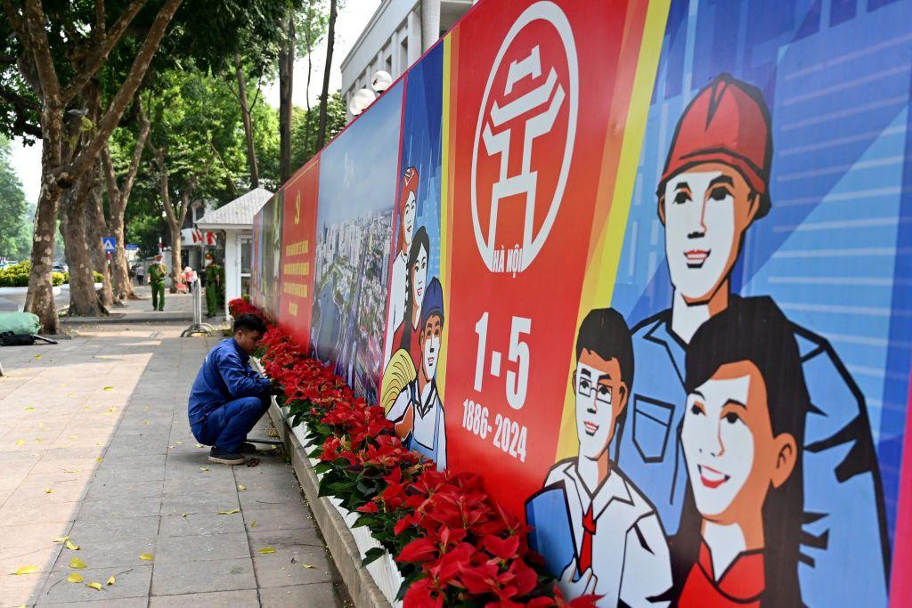 A worker plants flowers in front of a billboard marking the 1 May International Labour Day in Hanoi on 25 April 2024. (Photo by NHAC NGUYEN/AFP via Getty Images)