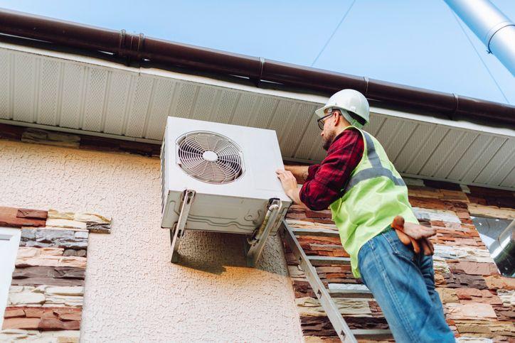 Homem instalando bomba de calor em casa