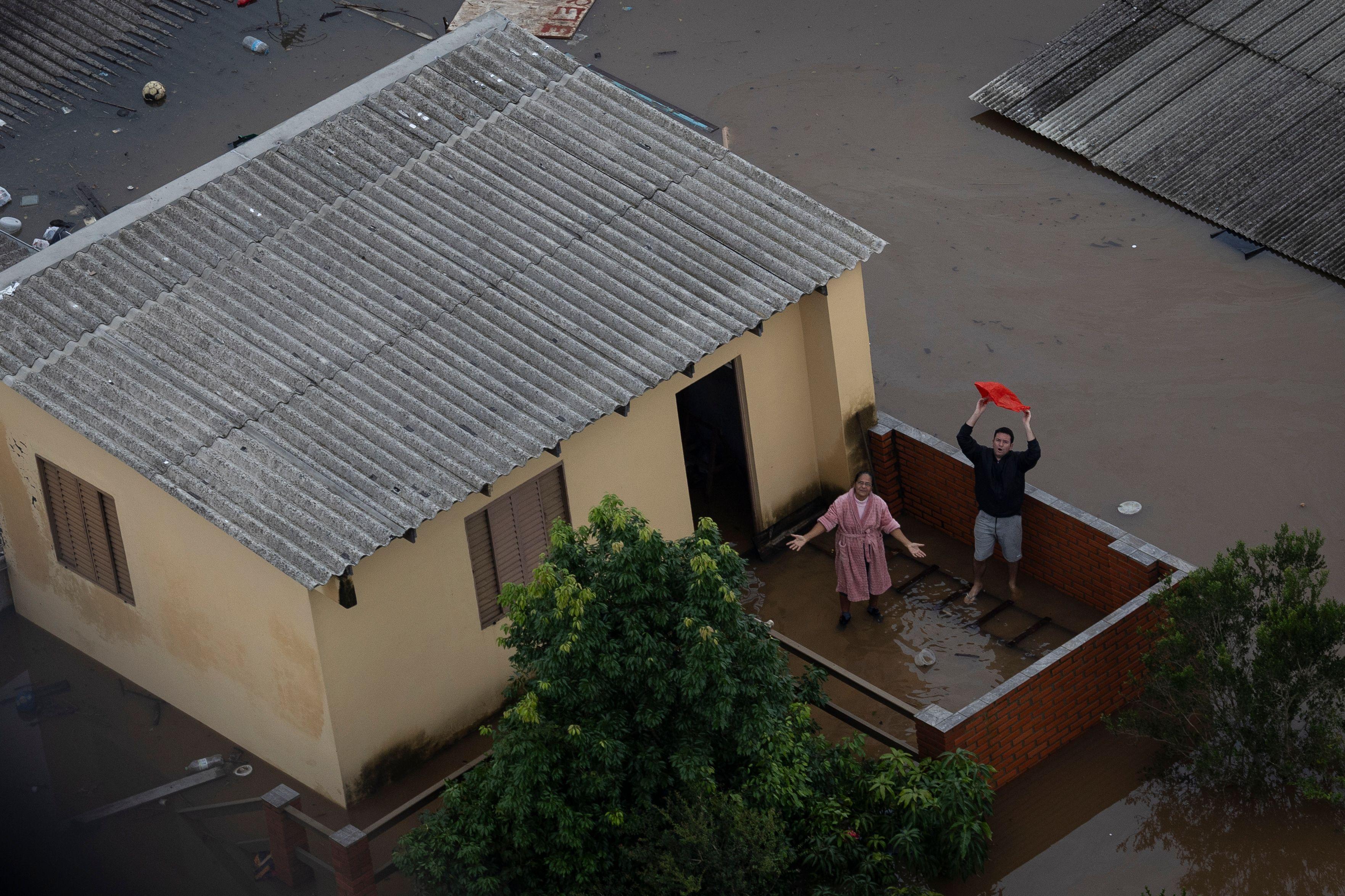 Pessoas pedindo ajuda em casa alagada