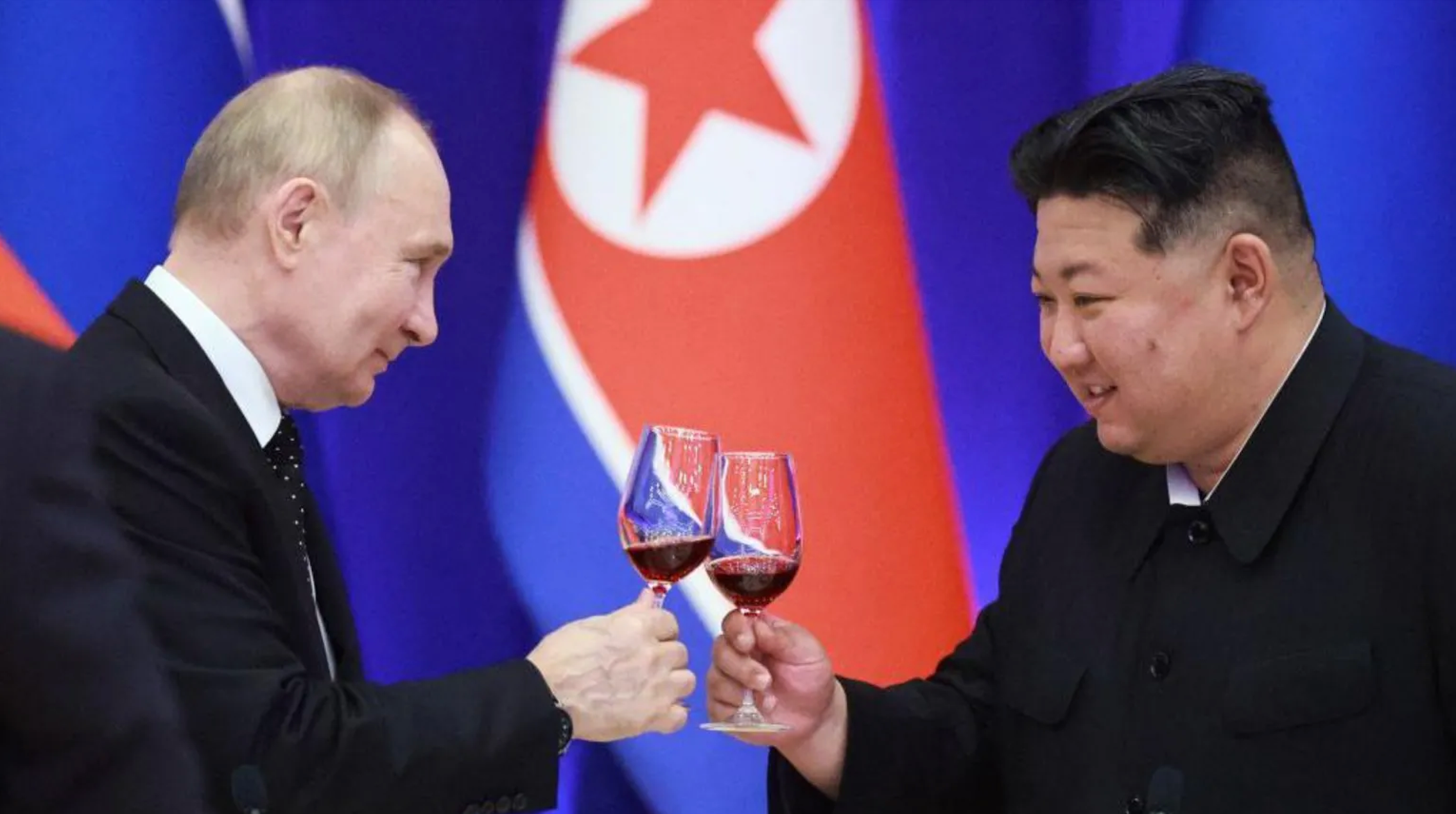 Sorridente, Vladimir Putin brinda com Kim Jong Un, com bandeira norte-coreana ao fundo