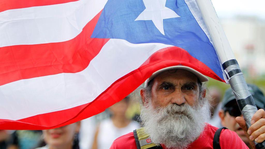 Un hombre sujeta la bandera de Puerto Rico en una manifestación en San Juan. 