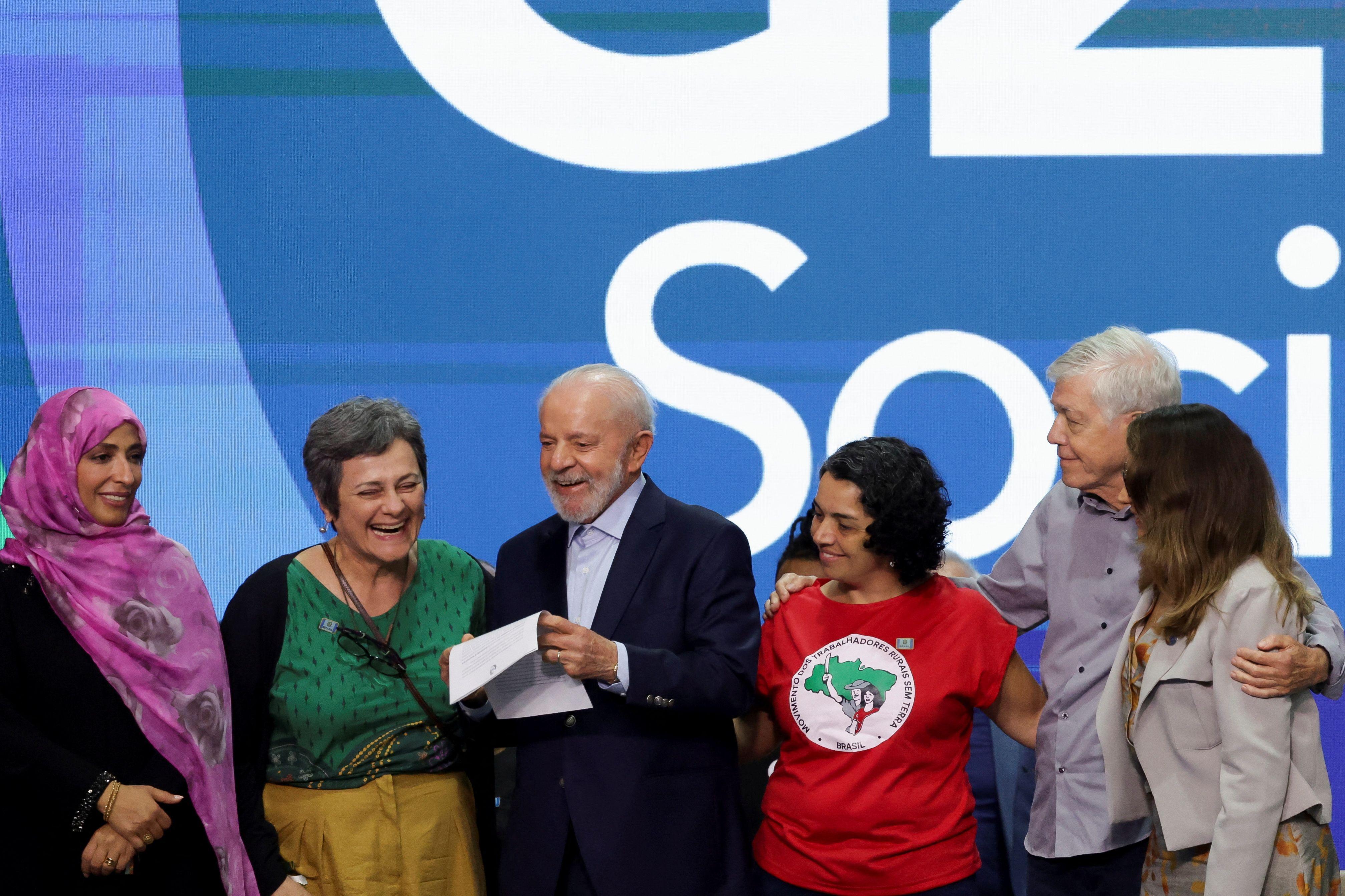 Lula com quatro mulheres e um homem abraços em palco do g20 social